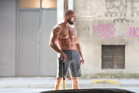 Athletic Man Resting - Workout At Gym With Hammer And Tractor Tireの写真素材