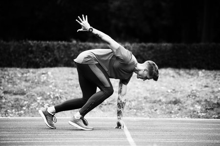 Athletic Man on Running Track Getting Ready to Start Run