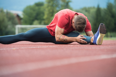 Young Athlete Man Relax and Strech Ready for Run at Athletics Race Track on Stadiumの写真素材