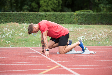 Fit and Confident Man in Starting Position Ready for Runningの写真素材