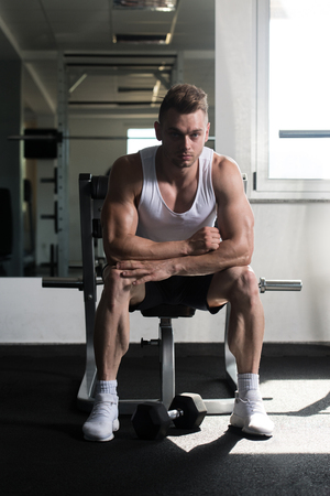 Attractive Man Resting On Bench After Exercise In Fitness Centerの写真素材
