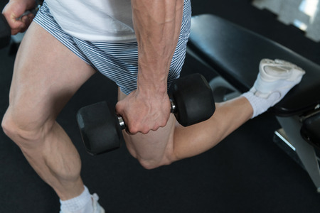 Athlete Working Out Hamstrings In A Gym With Dumbbellsの写真素材