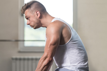 Muscular Man Stretches In A Gym And Flexing Muscles - Muscular Athletic Bodybuilder Fitness Modelの写真素材