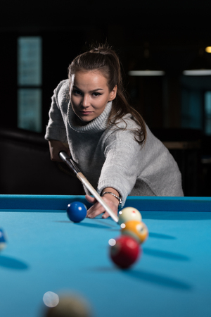 Young Woman Lining To Hit Ball On Pool Tableの写真素材