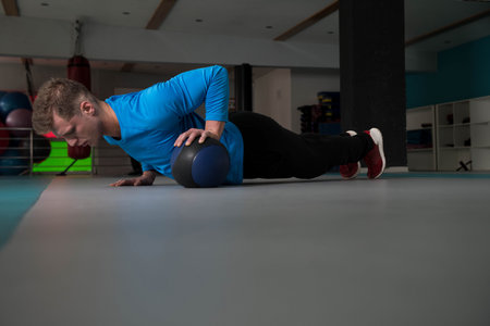 Handsome Young Man Doing Pushups With Medicine Ball As Part Of Bodybuilding Training
