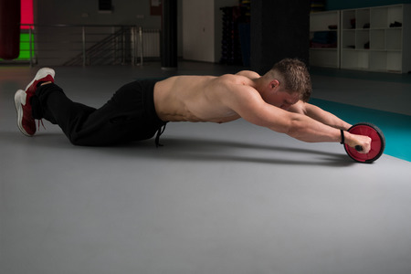 Young Man Exercising Fitness Workout For Abdominal With Toning Wheelの写真素材