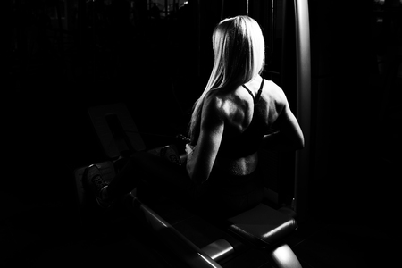 Fitness Woman Working Out Back On Machine In Fitness Centerの写真素材