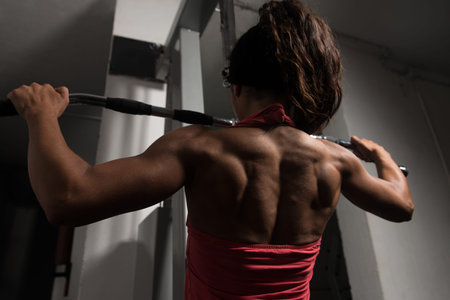 Young Fitness Woman Working Out Back On Machine In Fitness Center