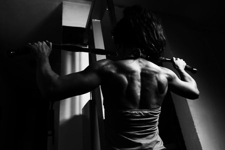 Young Woman Exercising Back On Machine In The Gym And Flexing Muscles - Muscular Athletic...