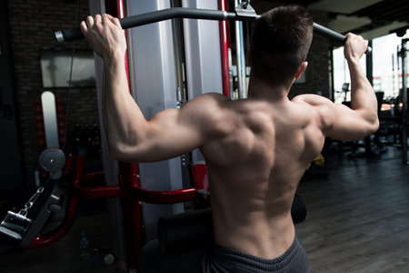 Handsome Bodybuilder Doing Heavy Weight Exercise For Back On Machine
