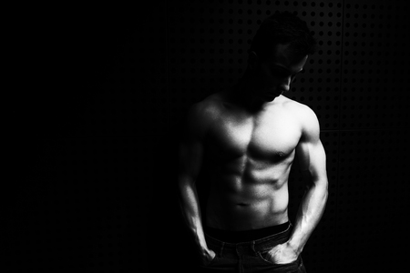 Portrait of a Young Physically Fit Man Showing His Well Trained Body While Wearing Blue Jeans - Muscular Athletic Bodybuilder Fitness Model Posing After Exercises on Wall Near the Wall - a Place for Your Textの写真素材