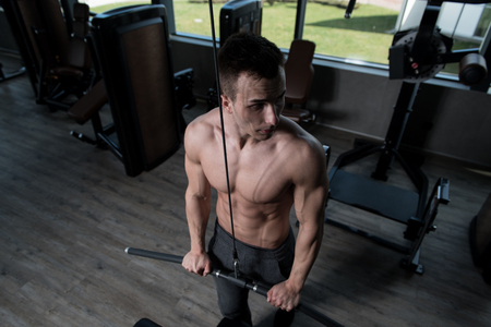 Young Muscular Fitness Bodybuilder Doing Heavy Weight Exercise For Triceps On Machine In The Gymの写真素材