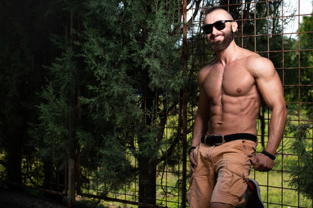 Portrait of a Young Physically Fit Man Showing His Well Trained Body - Muscular Athletic Bodybuilder Fitness Model Posing Outdoors - a Place for Your Textの写真素材