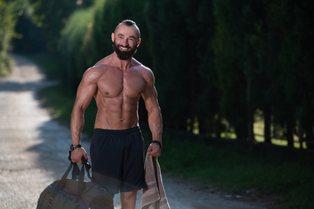 Beard Man Wearing a Sports Bag Outdoors in Park and Is Going to Fitness Center in Gymの写真素材