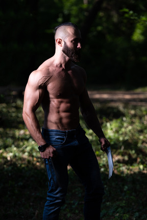 Superhero With Claws Standing Strong Flexing Muscles - Muscular Athletic Bodybuilder Fitness Wolverine Posing Outdoorsの写真素材