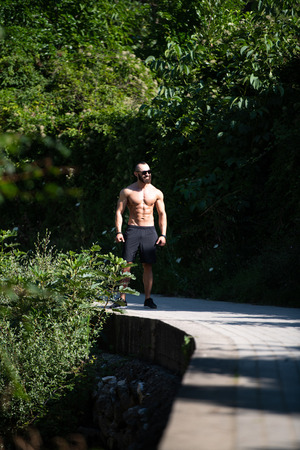 Handsome Beard Man Standing Strong and Posing at Outdoors - Background Nature of Leavesの写真素材