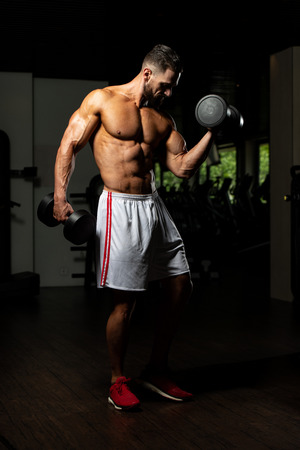 Athlete Working Out Biceps In A Gym - Dumbbell Concentration Curlsの写真素材