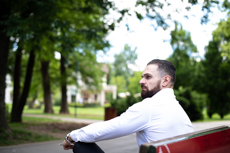 Portrait Of A Young Physically Fit Businessman Smokes Cuban Cigar in Parkの写真素材