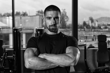 Portrait Of Handsome Personal Trainer Wearing Sportswear In Fitness Center Gym Standing Strongの写真素材