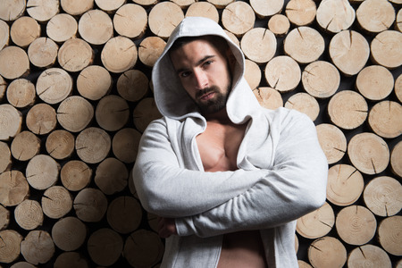 Healthy Young Man Standing Strong Standing Against a Wall and Flexing Muscles In Sweatshirt - Muscular Athletic Bodybuilder Fitness Model Posing After Exercises - a Place for Your Textの写真素材