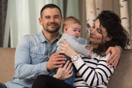 Mother and Father Playing With Their Cute Baby on the Couch at Home