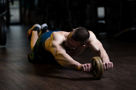 Young Man Wearing Glasses Exercising Fitness Workout For Abdominal With Toning Wheelの写真素材