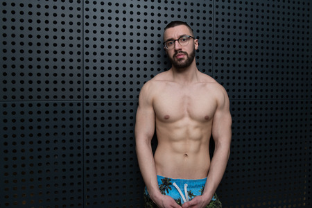Portrait of a Young Physically Fit Man Showing His Well Trained Body - Muscular Athletic Bodybuilder Fitness Model Posing After Exercises on Wall Near the Wall - a Place for Your Textの写真素材