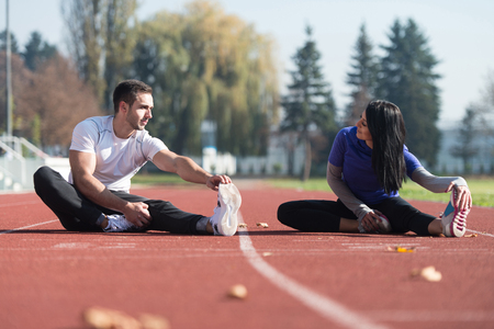Young Couple Stretching Before Running In City Park Area - Training And Exercising For Trail Run Marathon Endurance - Fitness Healthy Lifestyle Concept Outdoorの写真素材