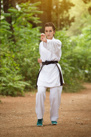 Young Woman Dressed In Traditional Kimono Practicing Her Karate Moves in Wooded Forest Area - Black Beltの写真素材
