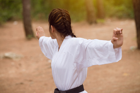 Young Woman Dressed In Traditional Kimono Practicing Her Karate Moves in Wooded Forest Area - Black Beltの写真素材