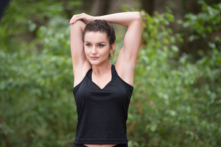 Young Woman Stretching Before Running In Wooded Forest Area - Training And Exercising For Trail Run Marathon Endurance - Fitness Healthy Lifestyle Conceptの写真素材