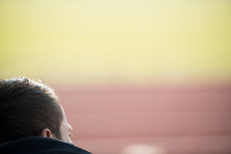 Back View of Young Man Sitting on Seat or Bleachers Sports Tribune and Cheering for His Favourite...