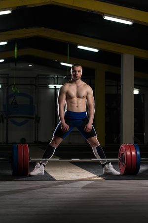 Strong Man Ready to Lift Heavy Barbell From Floor During Powerlifting Workout in Gymの写真素材