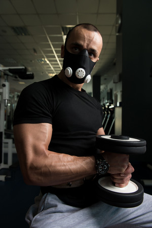 Athlete Working Out Biceps In Elevation Mask - Dumbbell Concentration Curlsの写真素材