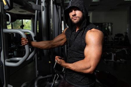 Muscular Fitness Bodybuilder Doing Heavy Weight Exercise For Biceps On Machine With Cable In The Gymの写真素材