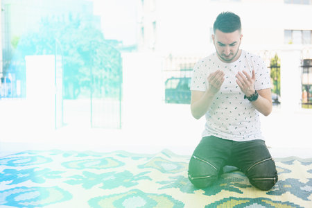 Attractive Man Making Traditional Prayer to God Allah Outdoors at Front the Mosque