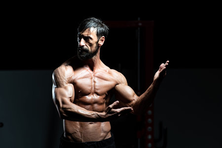 Middle Age Man Standing Strong In The Gym And Flexing Muscles - Muscular Athletic Bodybuilder...