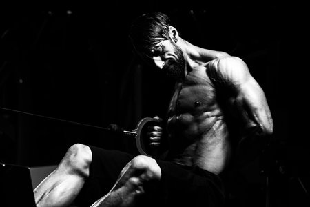 Handsome Athlete Doing Heavy Weight Exercise For Back On Machine