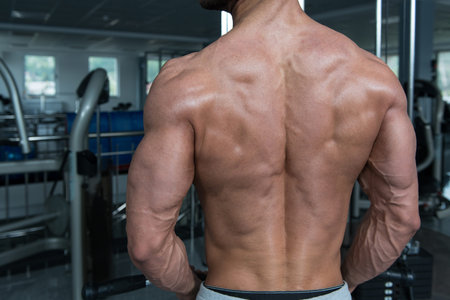 Handsome Athlete Doing Heavy Weight Exercise For Back On Machine