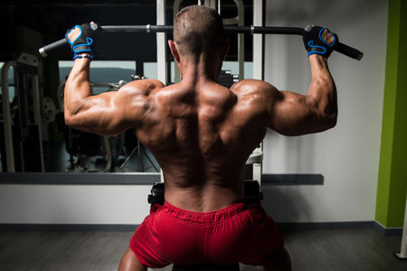 Handsome Athlete Doing Heavy Weight Exercise For Back On Machine