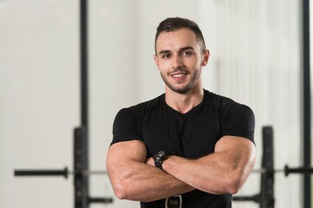 Handsome Personal Trainer With Stopwatch In A Fitness Center Gym Standing Strongの写真素材
