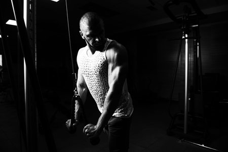 Muscular Fitness Bodybuilder Doing Heavy Weight Exercise For Triceps On Machine With Cable In The...