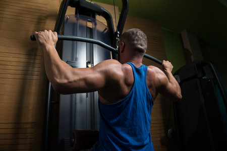 Handsome Athlete Doing Heavy Weight Exercise For Back On Machine