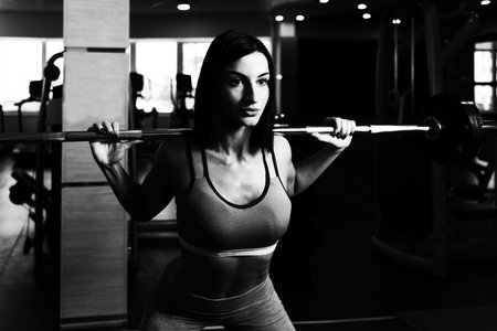 Healthy Fitness Woman Working Out Legs With Barbell In A Gym - Squat Exercise
