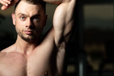 Handsome Young Man Standing Strong In The Gym And Flexing Muscles - Muscular Athletic Bodybuilder Fitness Model Posing After Exercisesの写真素材