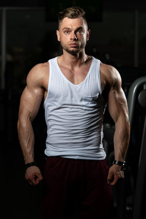 Healthy Young Man Standing Strong In The Gym And Flexing Muscles - Muscular Athletic Bodybuilder...