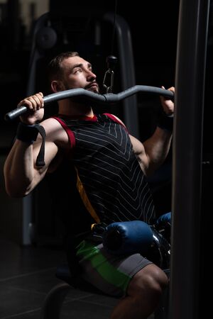 Handsome Athlete Doing Heavy Weight Exercise For Back On Machineの写真素材