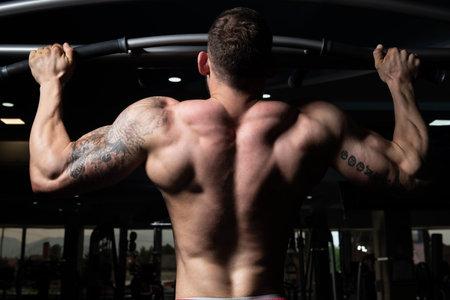 Handsome Bodybuilder Doing Heavy Weight Exercise For Back On Machine