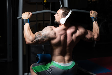 Handsome Athlete Doing Heavy Weight Exercise For Back On Machine