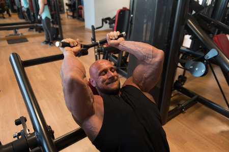 Muscular Fitness Bodybuilder Doing Heavy Weight Exercise For Triceps On Machine With Cable In The...